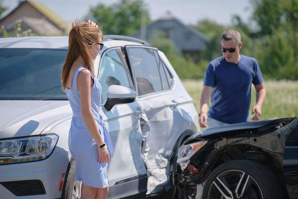 Female driver complaining the uninsured driver on the damages after the accident.