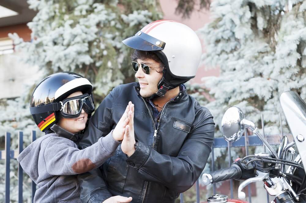 Father and son motorcyclists making high five.