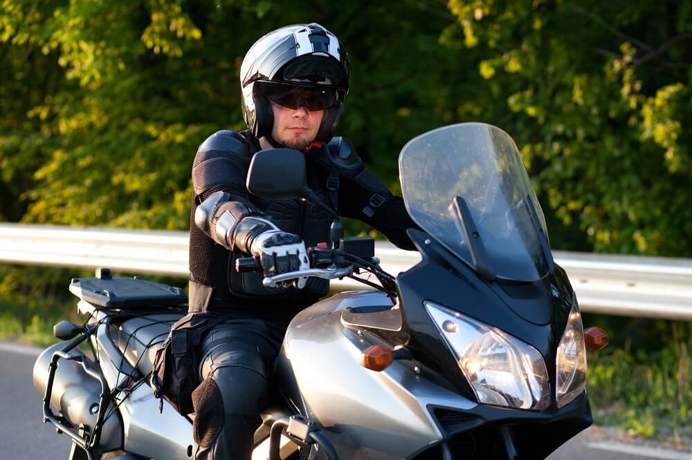 Motorcycle rider wearing safety gear while strolling.